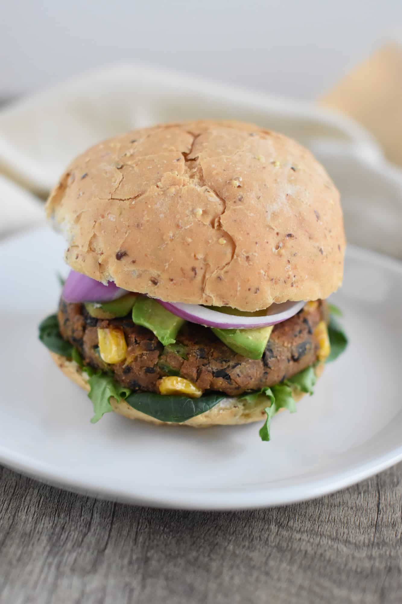sweet potato black bean burger on a bun with lettuce, avocado and red onion
