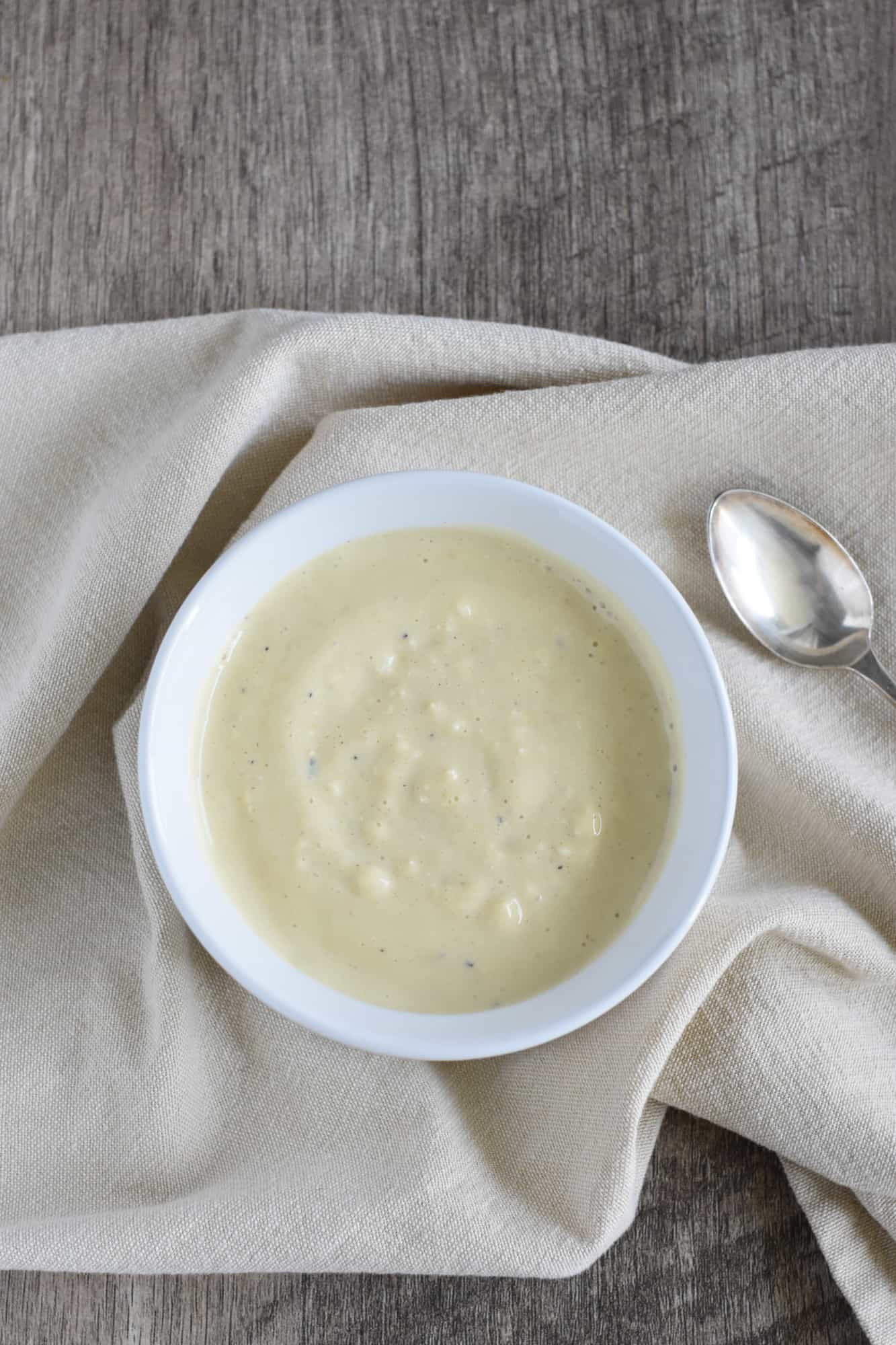 overhead of dressing in a white bowl with a spoon next to it
