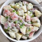 overhead of potato salad in a white bowl with a spoon in it