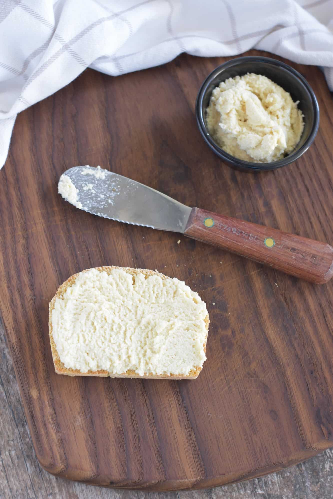 dairy-free ricotta spread onto one slice of toast on a wooden board