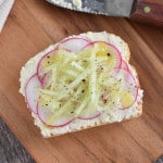 cucumber and radish vegan ricotta toast on a wooden board.
