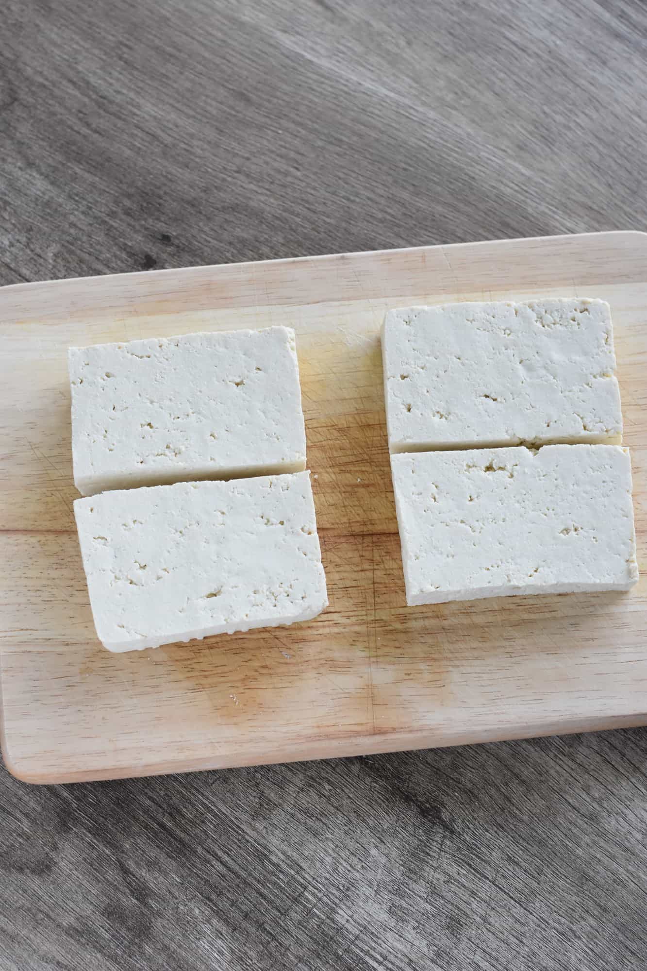 tofu cut into 4 pieces on cutting board