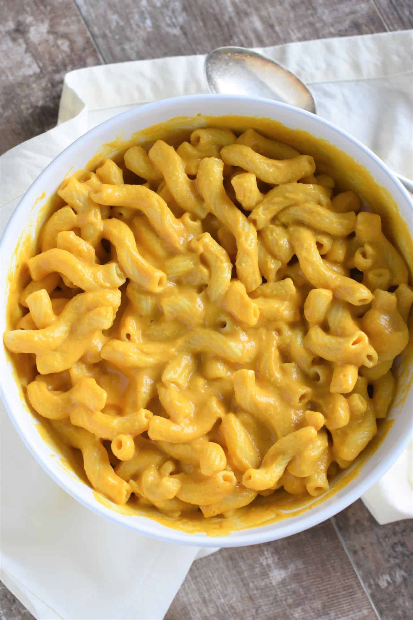 overhead of pasta mixed with cheese sauce in white serving bowl