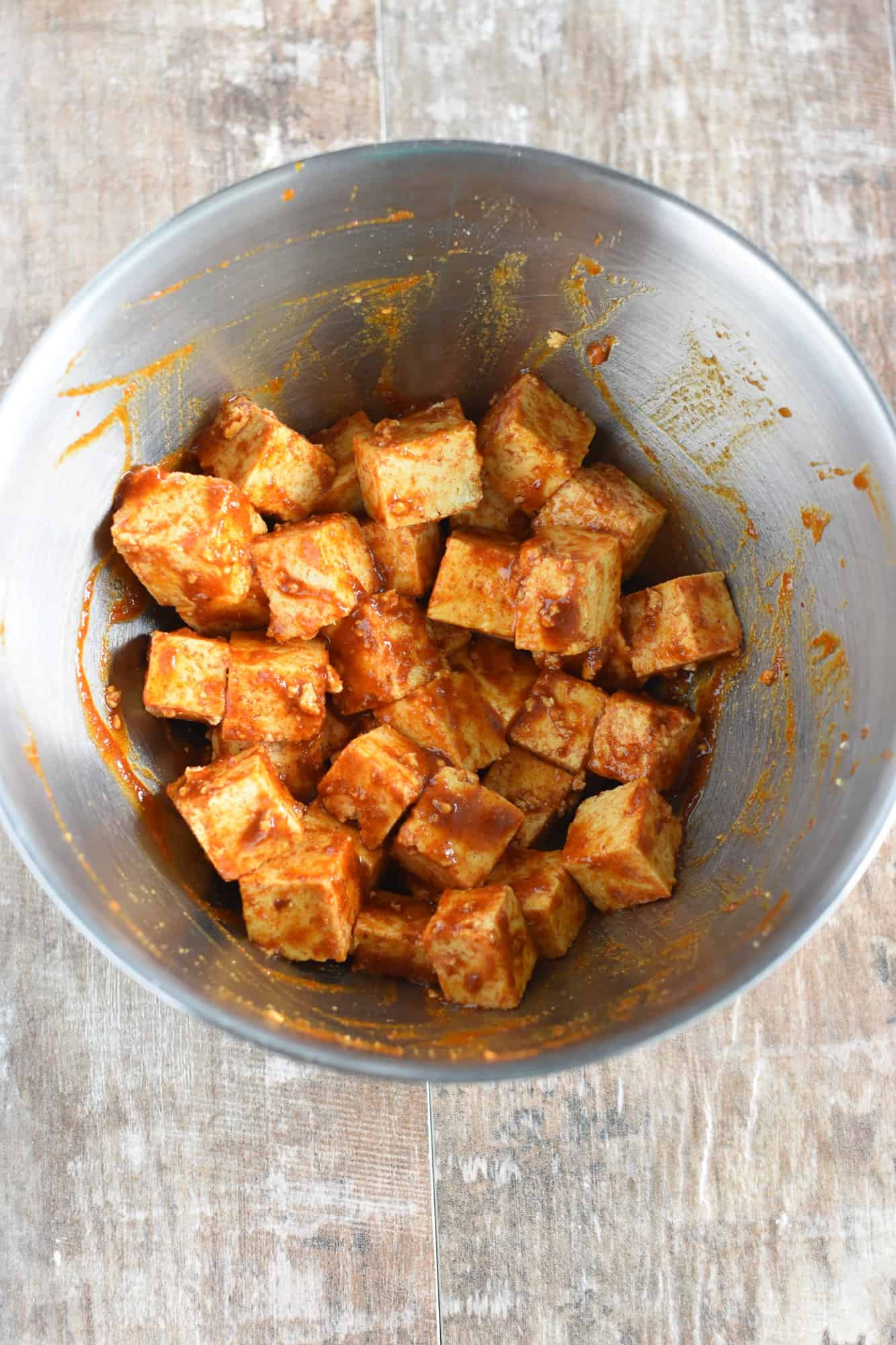 Tofu pieces coated with marinade in the mixing bowl