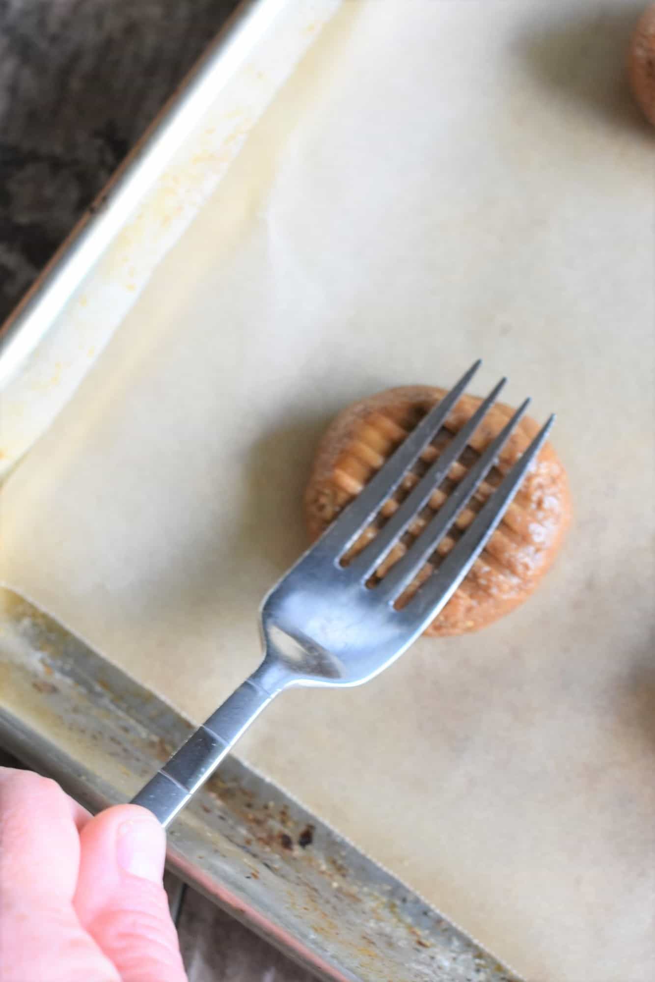 pressing down on one cookie dough ball with a fork going the other way