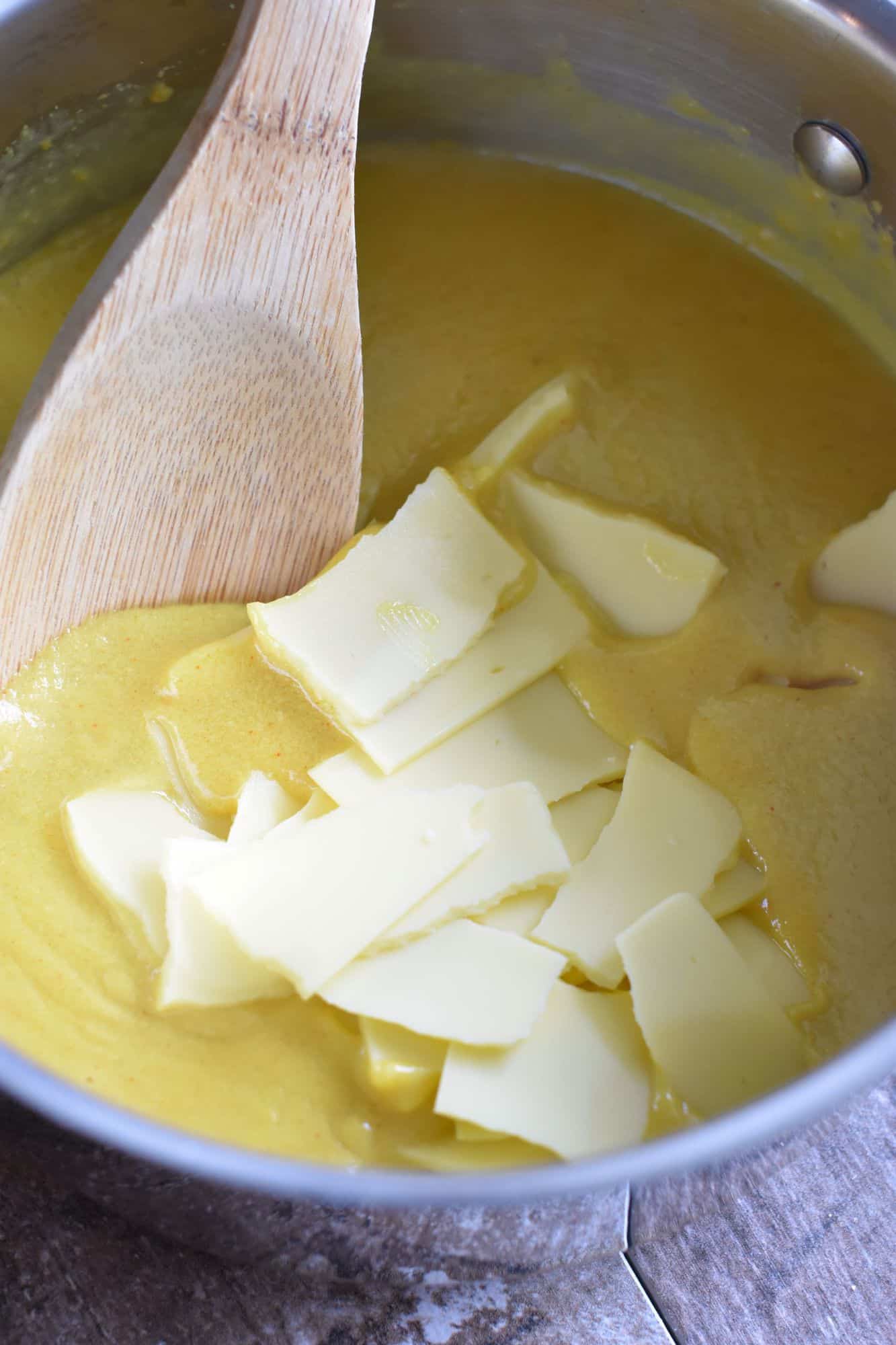 stirring vegan cheese into the mixture in the saucepan with a wooden spoon