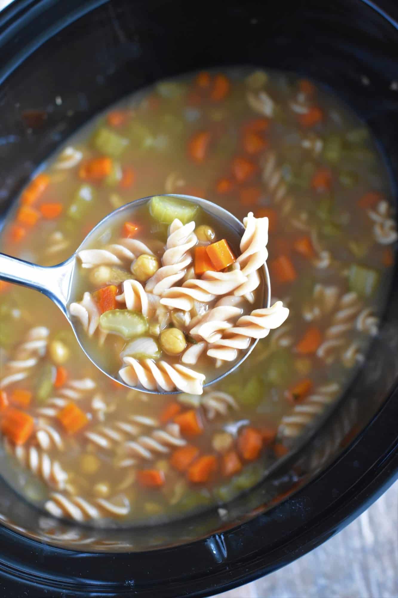 holding scoop of soup in a ladle over the slow cooker