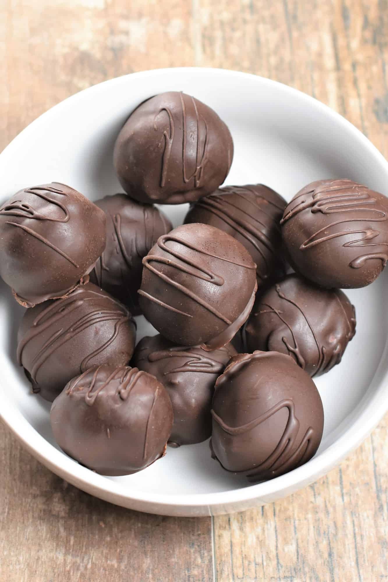 overhead of cookie balls covered in chocolate in a white bowl