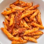 Pumpkin Tomato Pasta Sauce in a white bowl topped with vegan cheese