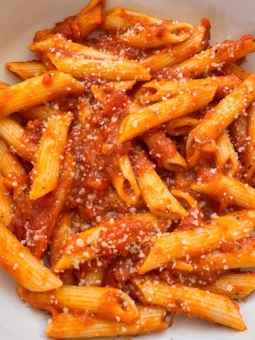 Pumpkin Tomato Pasta Sauce in a white bowl topped with vegan cheese