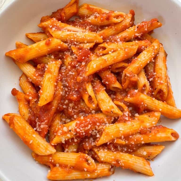 Pumpkin Tomato Pasta Sauce in a white bowl topped with vegan cheese
