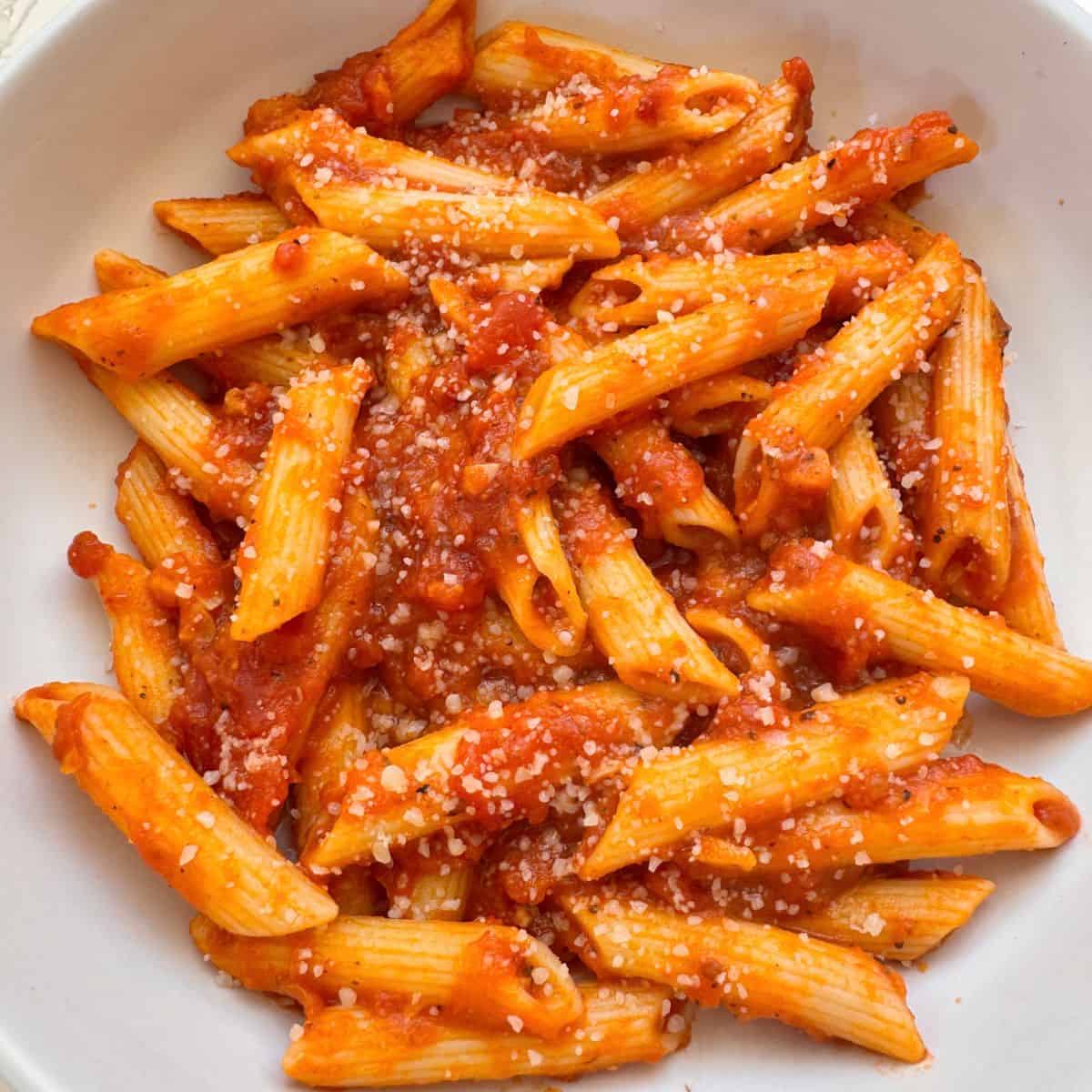 Pumpkin Tomato Pasta Sauce in a white bowl topped with vegan cheese
