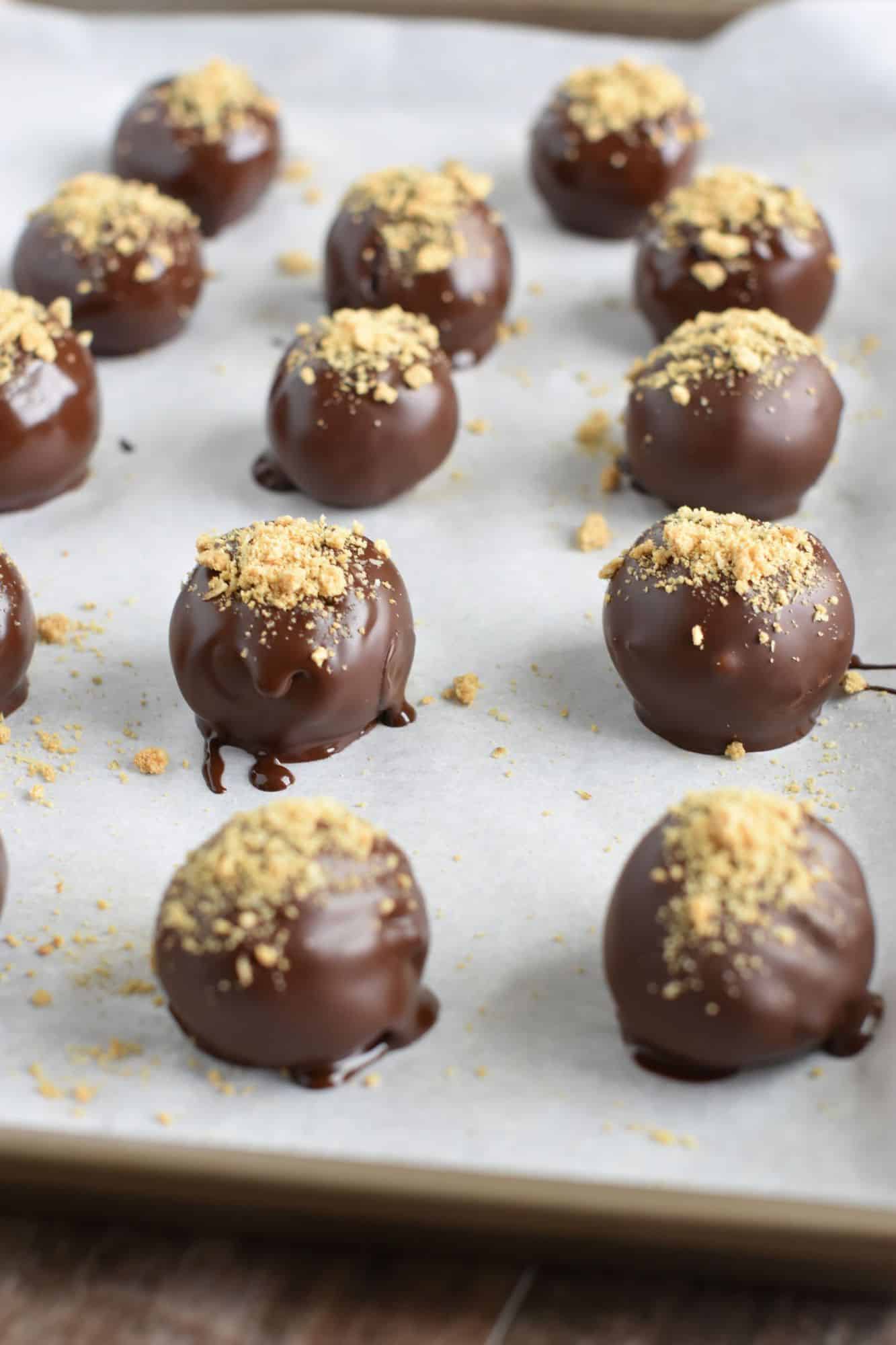 truffles coated with chocolate and topped with crumbled grahams on baking sheet