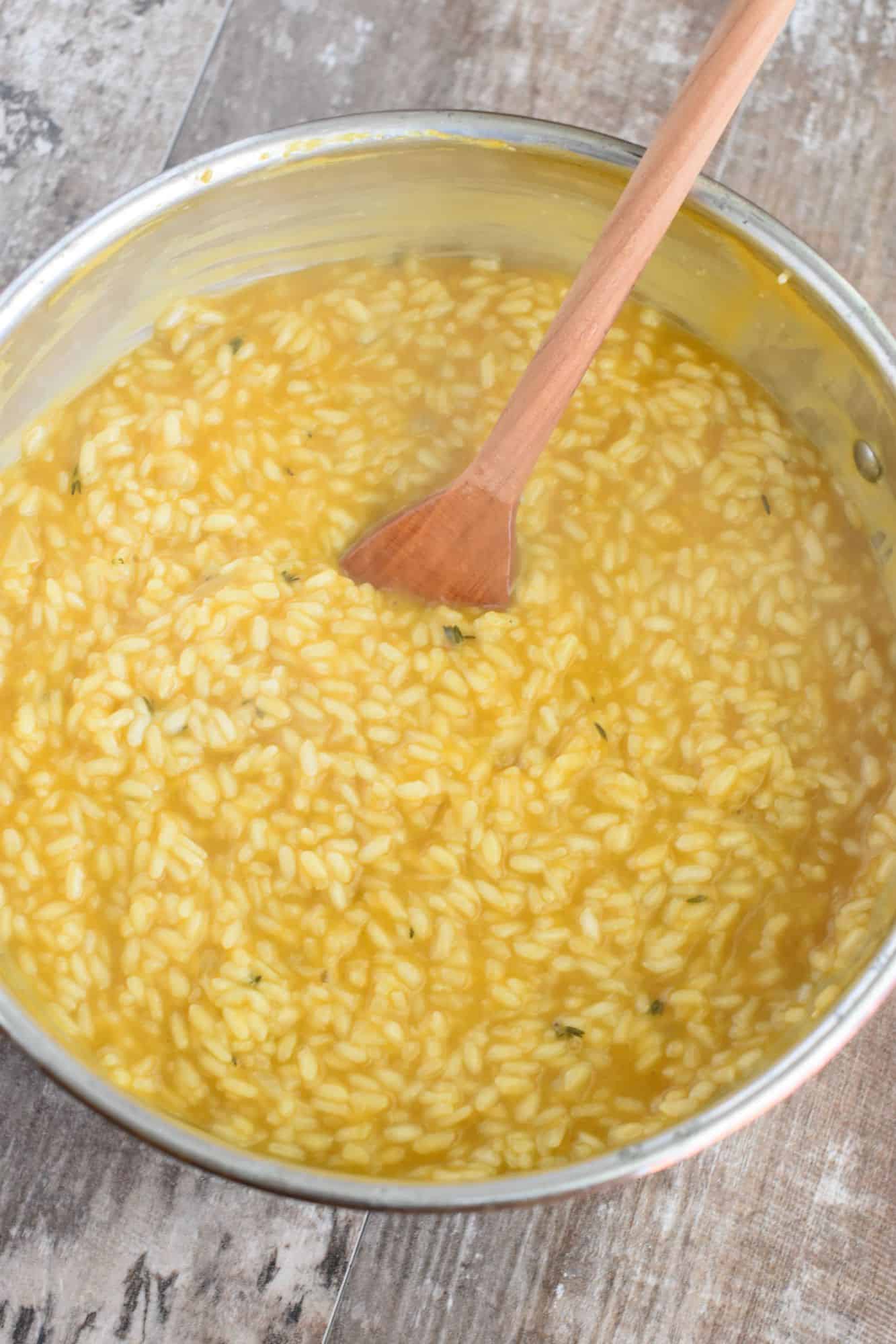 risotto in the pan with a wooden spoon before adding the nutritional yeast and cheese