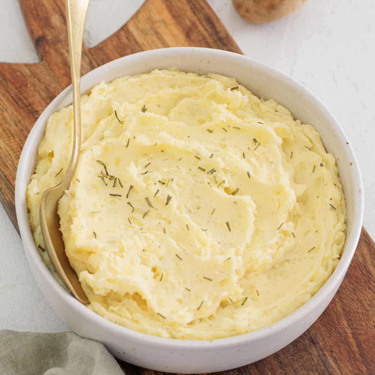 close-up overhead of mashed potatoes in white bowl with spoon in it