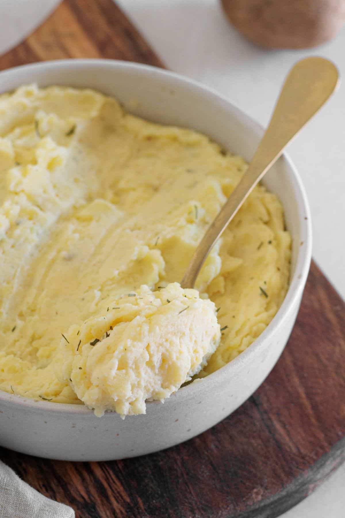 spoon full of dairy free mashed potatoes sitting on top of the bowl of mashed potatoes.
