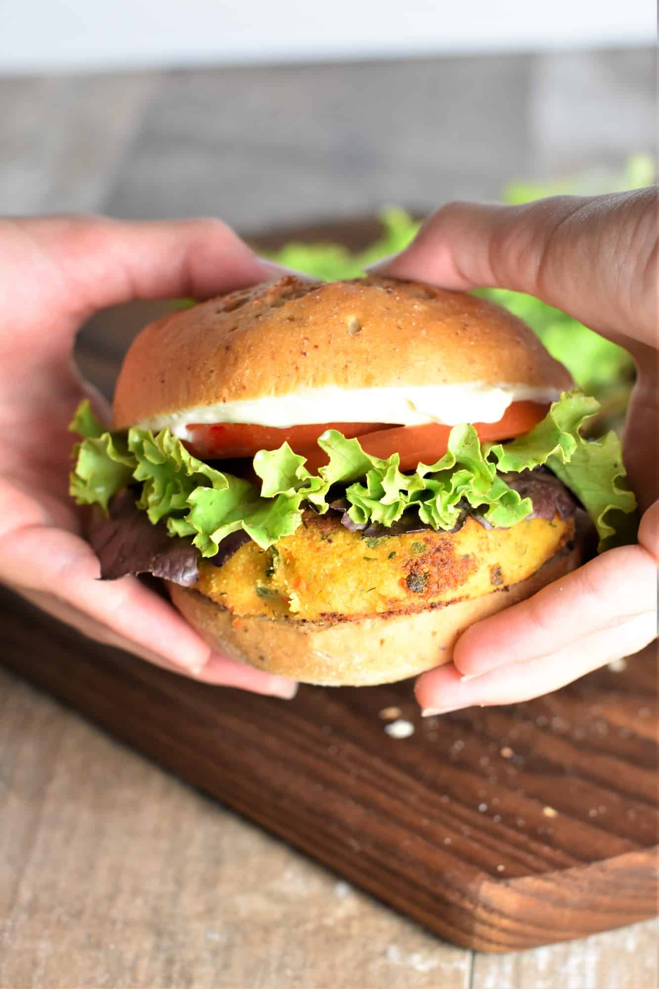 front view of hands holding vegan chickpea burger