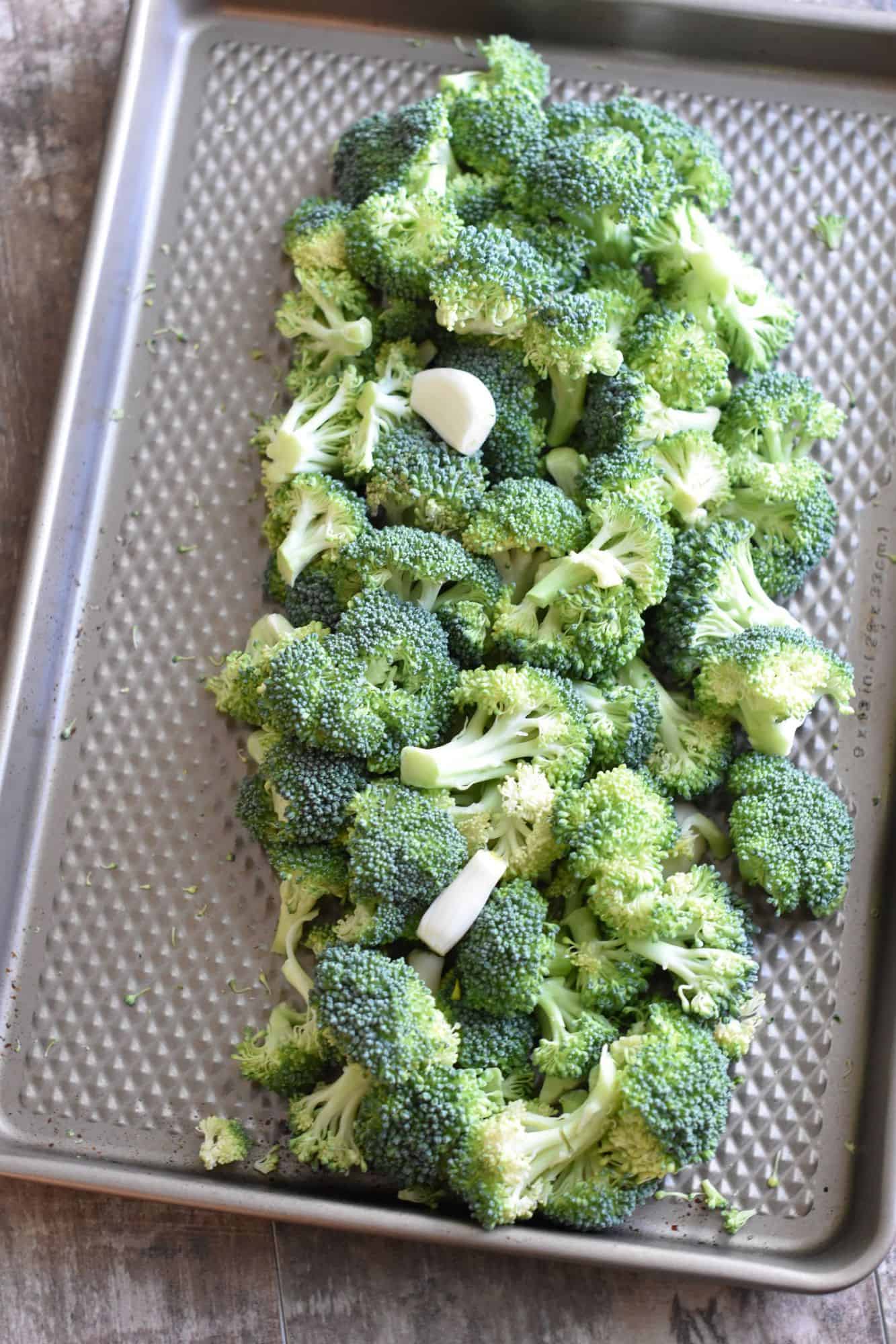 uncooked broccoli and garlic in pile on baking sheet