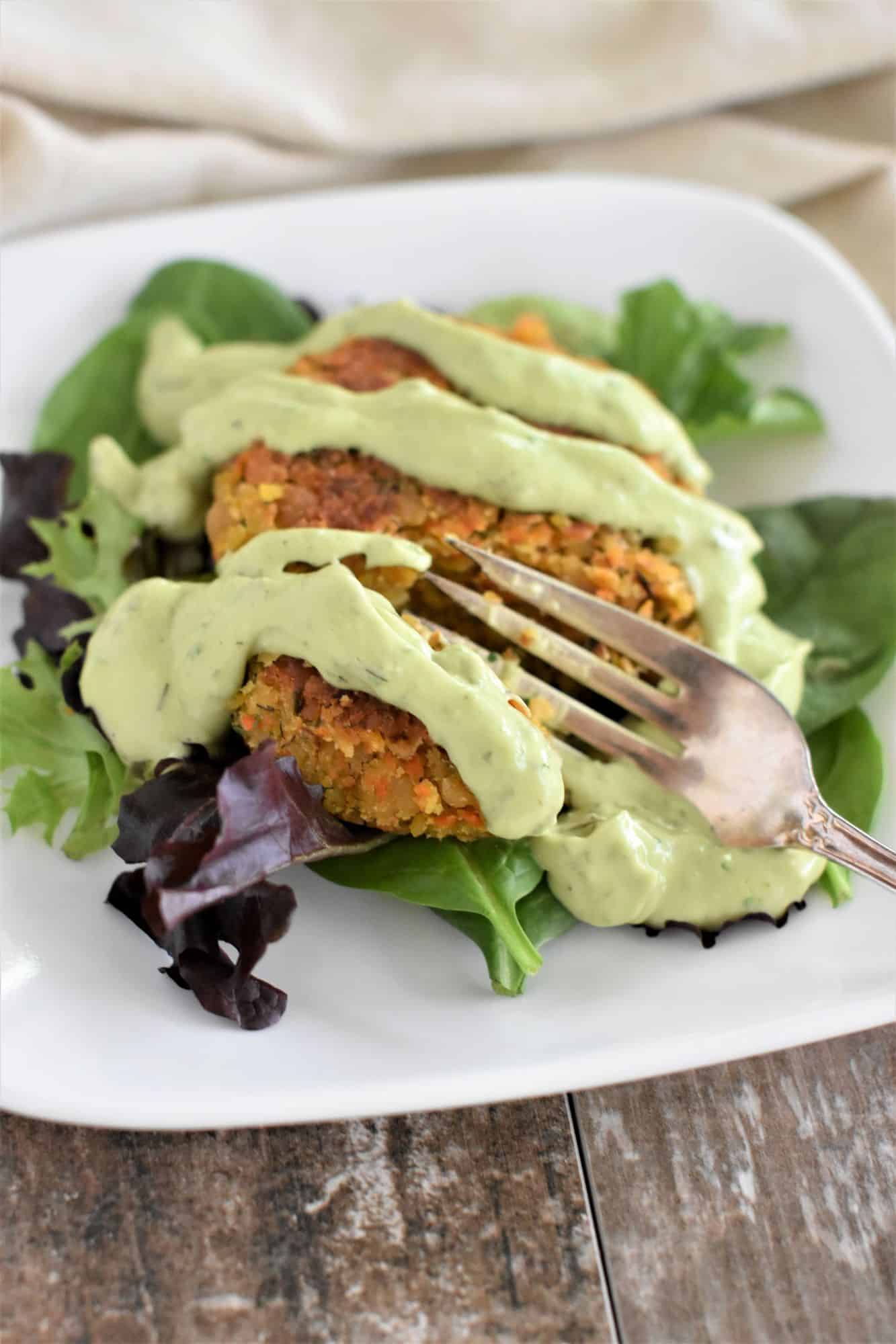 fork cutting into chickpea burger with avocado ranch dressing 