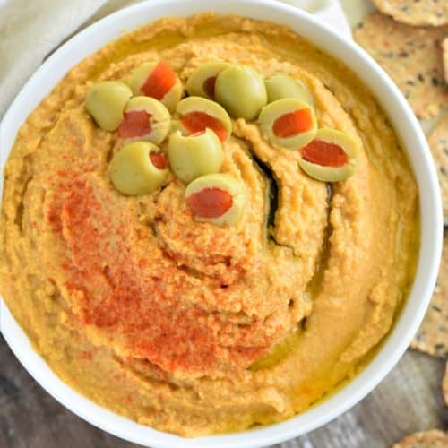 close-up overhead of hummus in white bowl with crackers around it