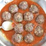 close-up overhead of meatballs in sauce in saucepan with a spoon in it