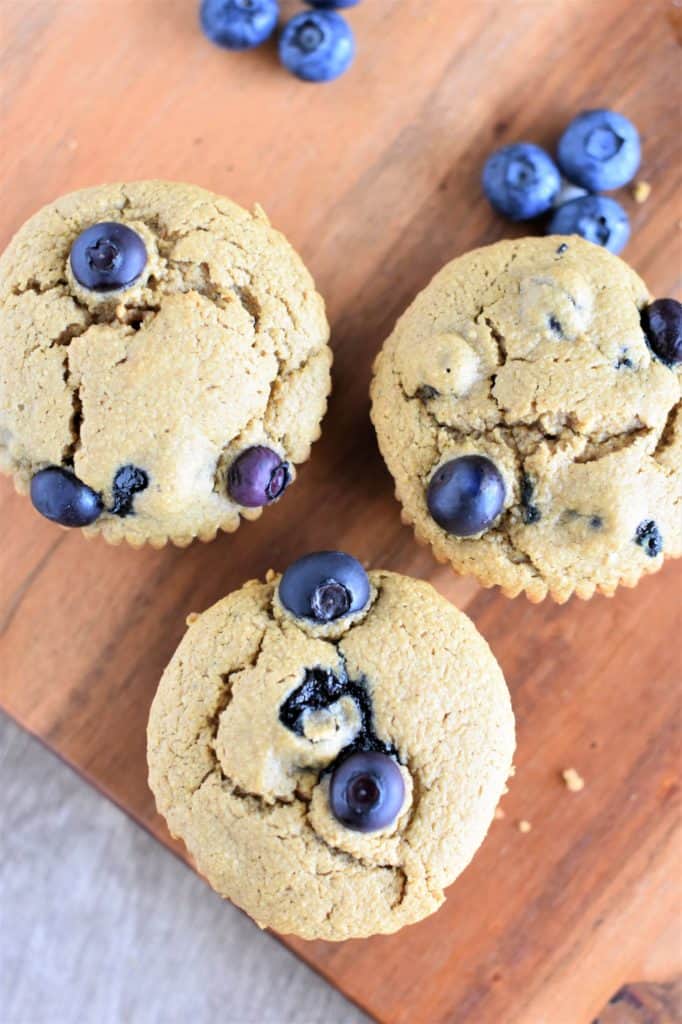 overhead of three vegan blueberry muffins on a wood board