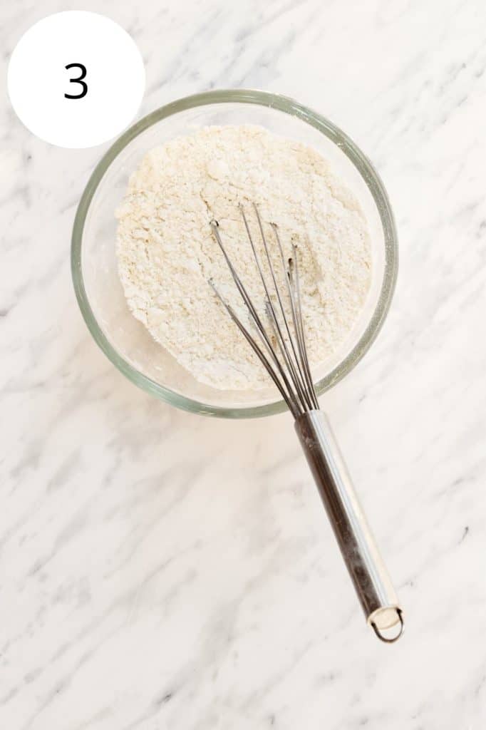 Dry ingredients in mixing bowl with whisk in it
