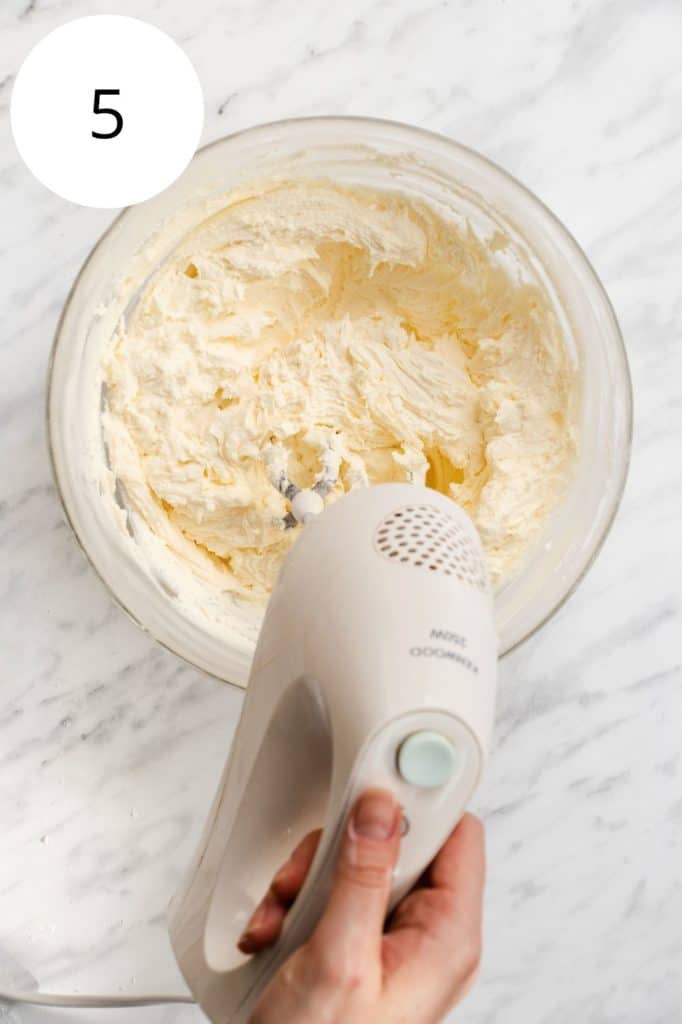 using electric hand mixer to beat the frosting
