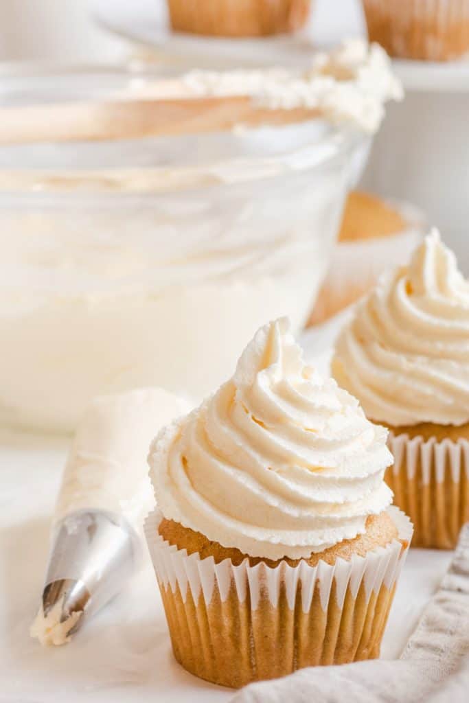 close-up of frosted cupcake with piping bag of frosting next to it