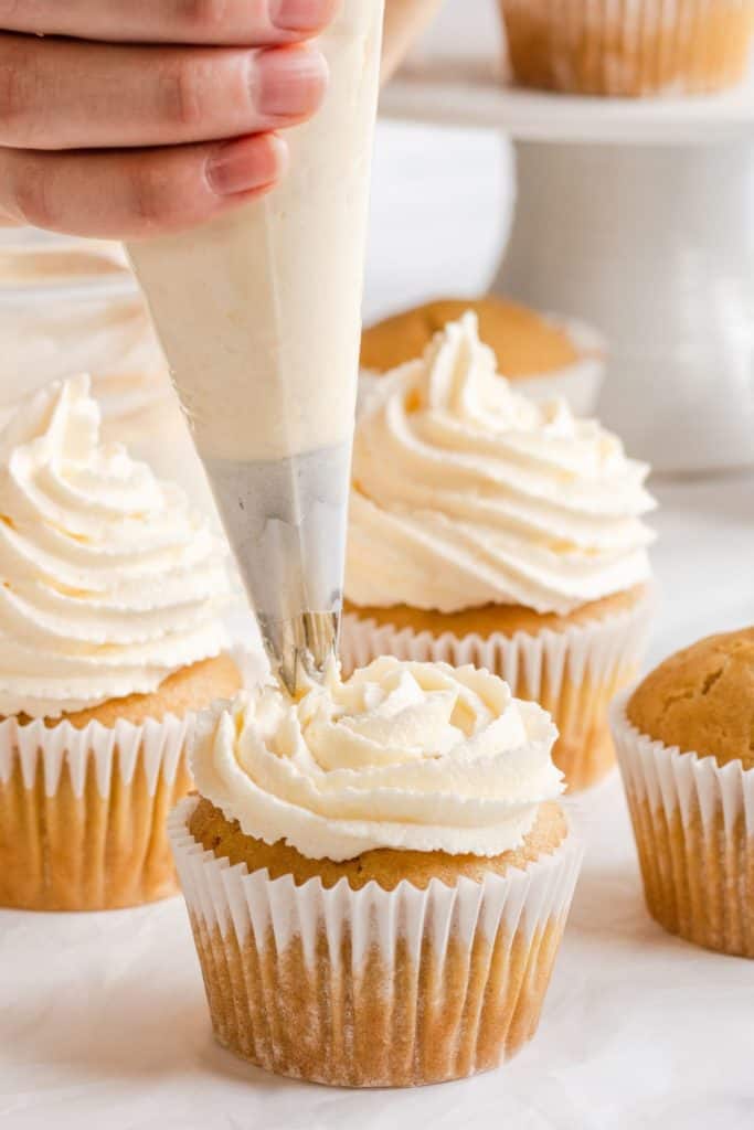 frosting a cupcake using a piping bag