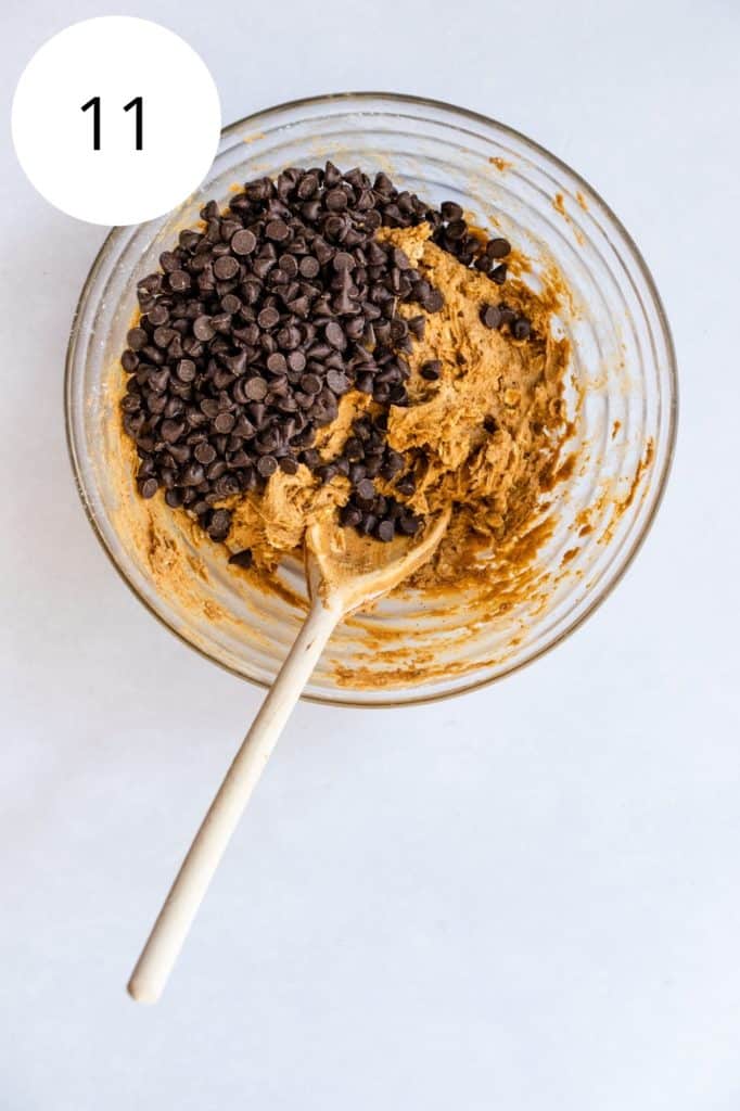 chocolate chips added to dough in mixing bowl with wooden spoon