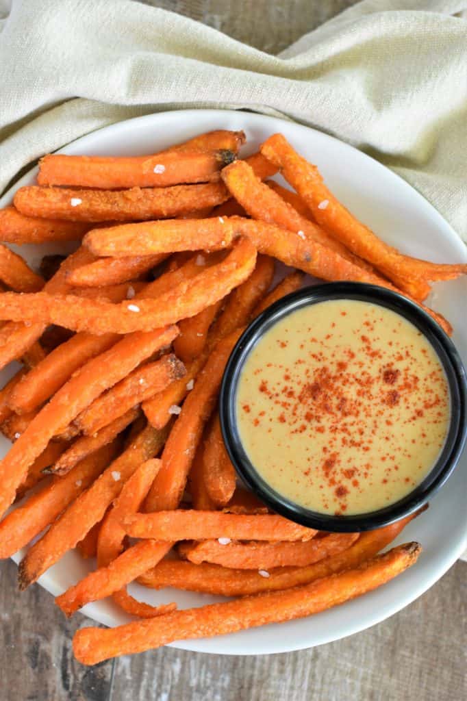 overhead of dipping sauce in a small serving cup on a plate of sweet potato fries