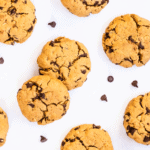 close-up overhead of cookies on a white surface with chocolate chips around