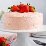 close-up front view of vegan strawberry cake on a white cake stand