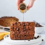 pouring maple syrup on a stack of banana bread slices