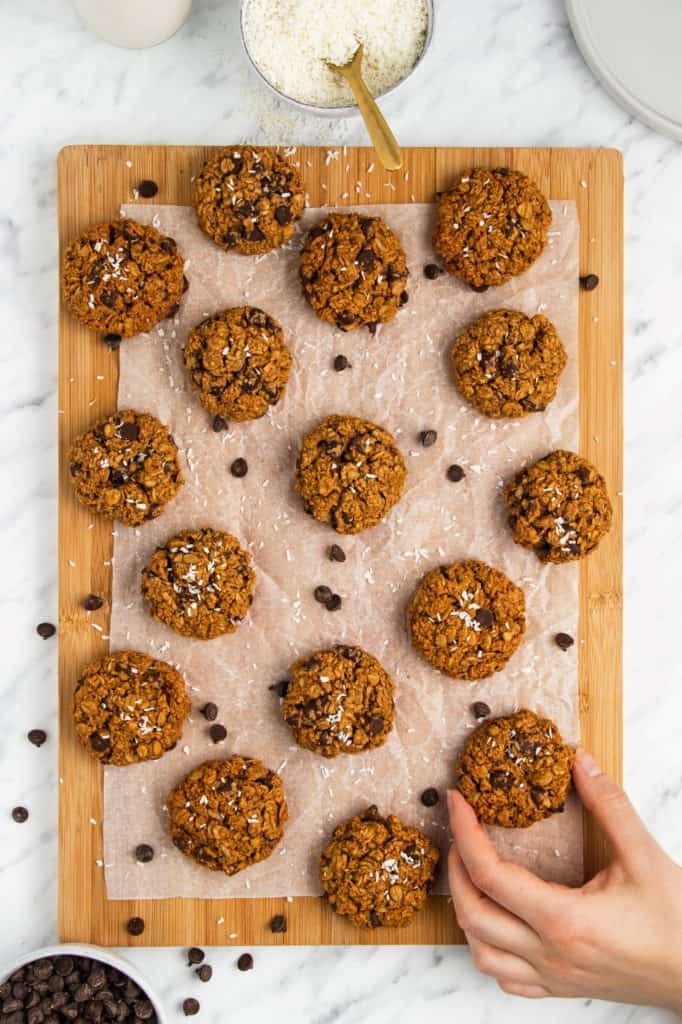 cookies on parchment on wooden board with a hand grabbing one