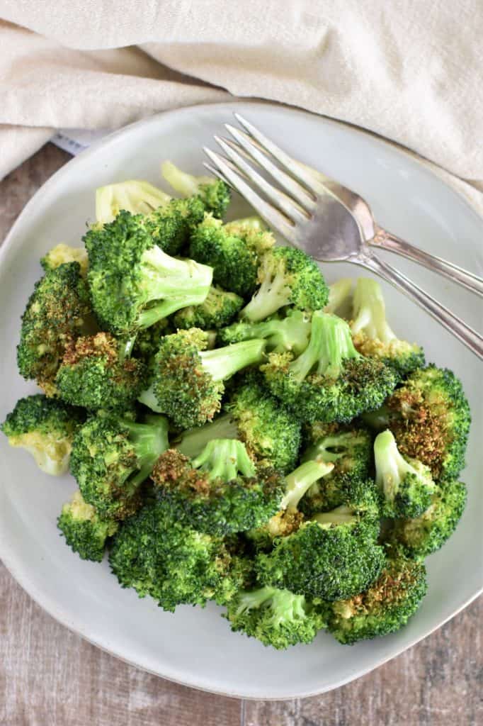 overhead shot of air fryer broccoli on a white plate with two forks on the plate