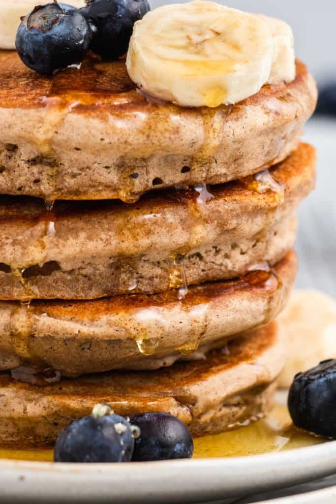 close-up of stack of pancakes on a plate with maple syrup dripping down the side