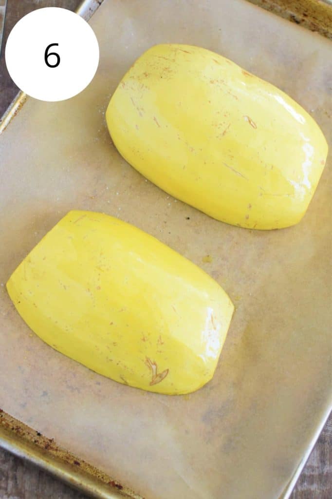 spaghetti squash halves flipped over with outer part exposed on baking sheet