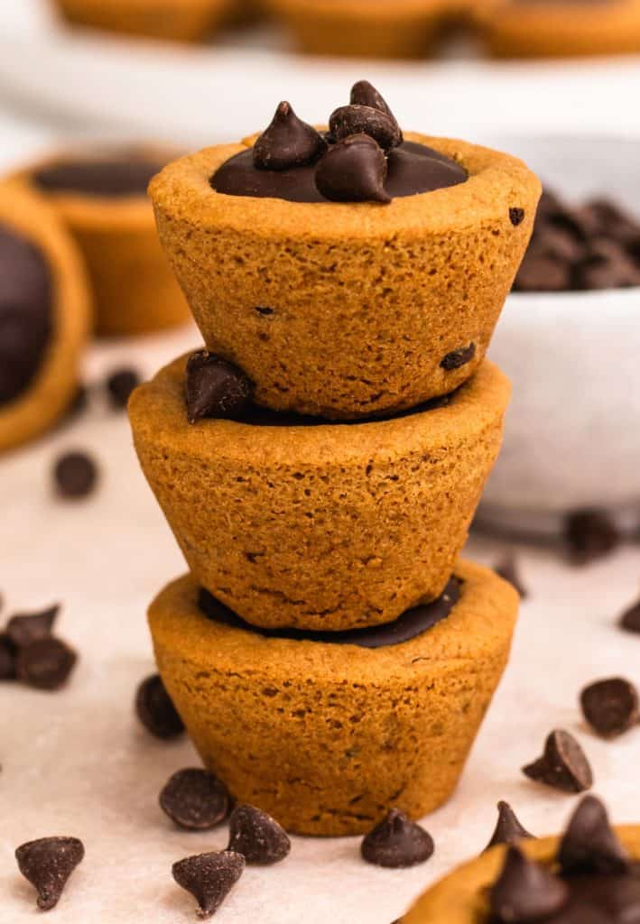 three cookie cups stacked on top of each other with some chocolate chips around