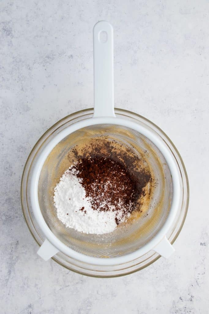 sifting cocoa powder and powdered sugar into the butter