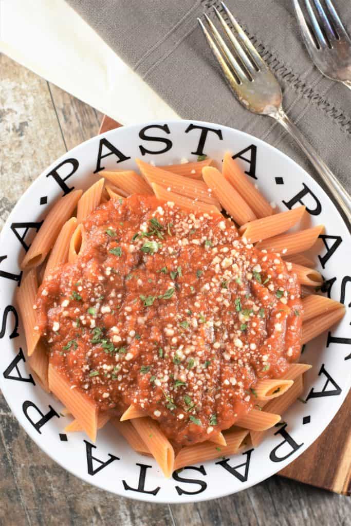 overhead of pasta in a pasta bowl with sauce and garnished with grated cheese and parsley