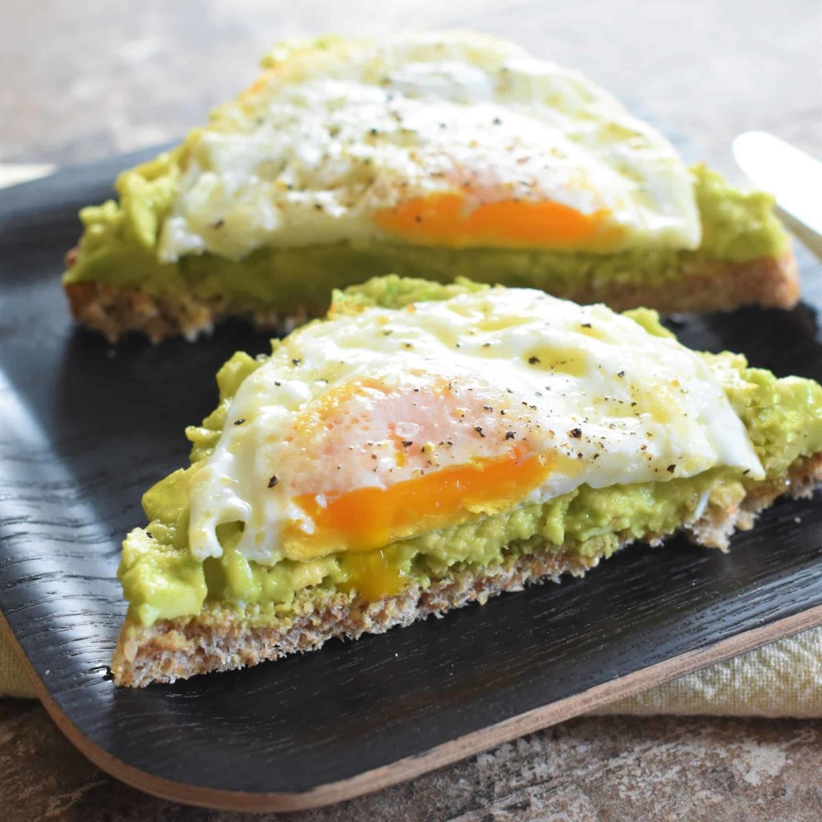 close-up of cut slice of avocado toast with fried egg