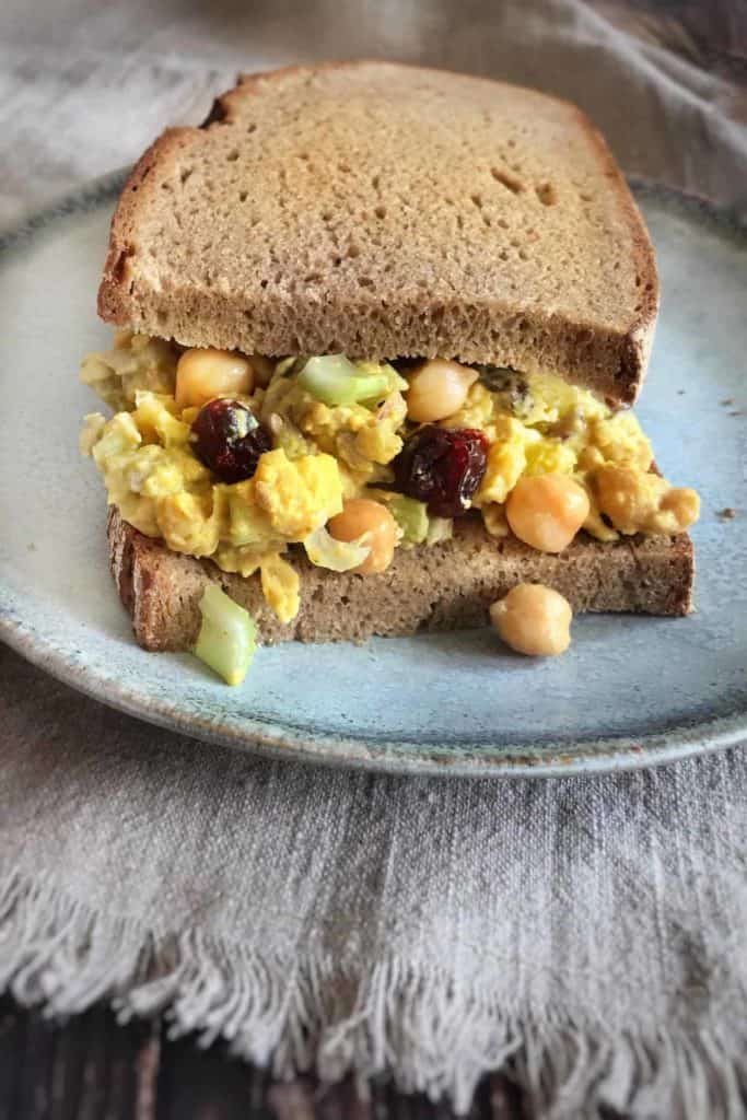 curry chickpea salad sandwich on a plate on a kitchen towel