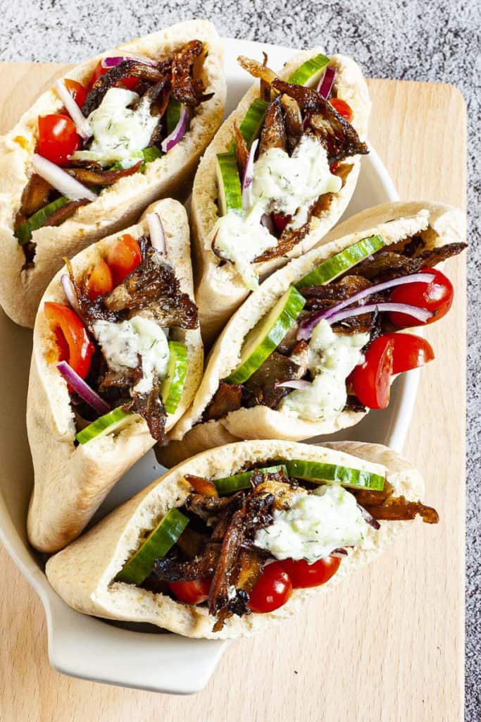 vegan gyros in white serving dish topped with tzatziki sauce