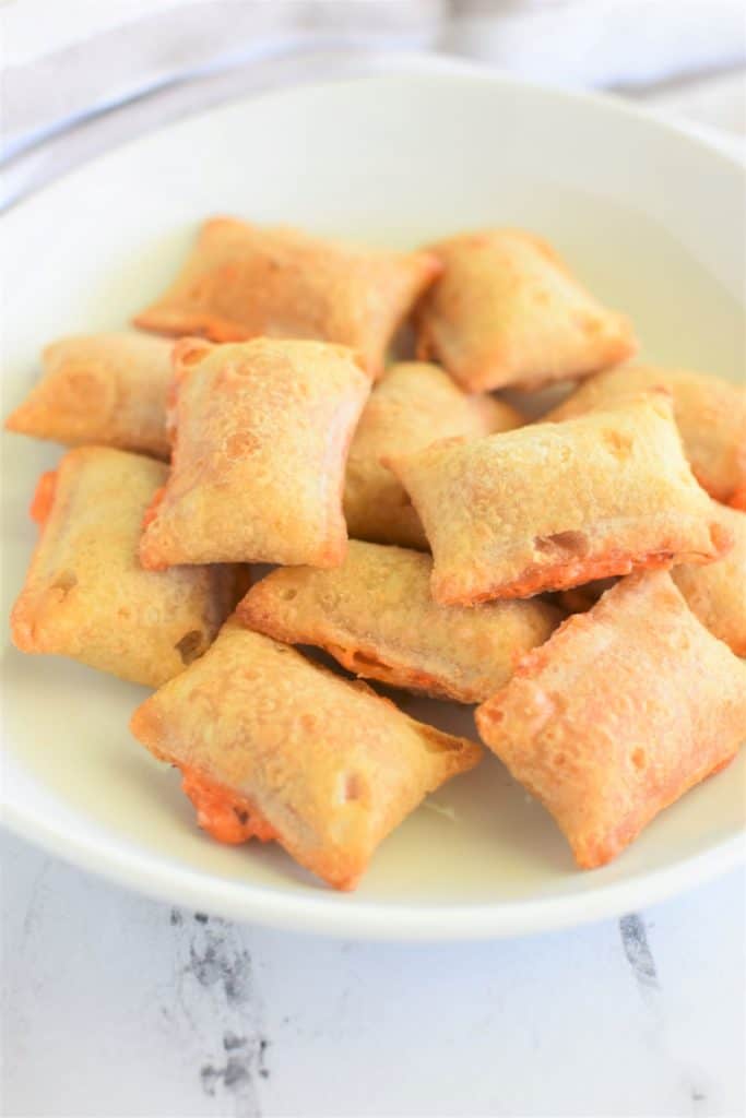 front view of pizza rolls on white plate with some cheese oozing out