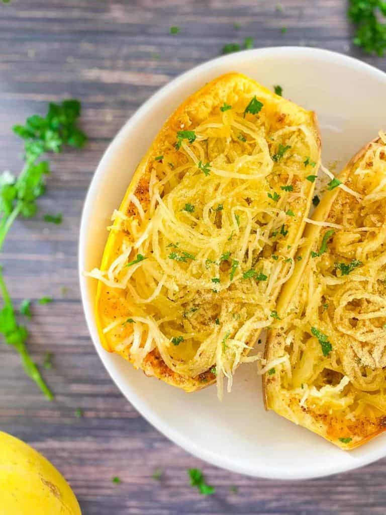 air fryer spaghetti squash in white serving bowl topped with vegan Parmesan and parsley