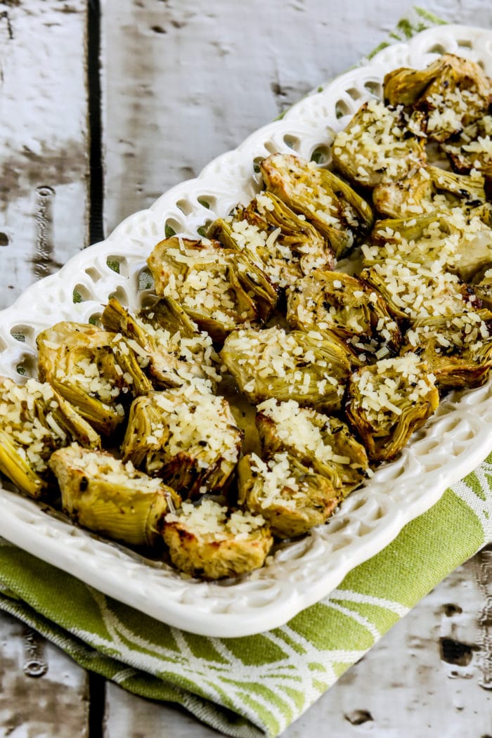 air fryer artichokes on white serving platter on green kitchen towel