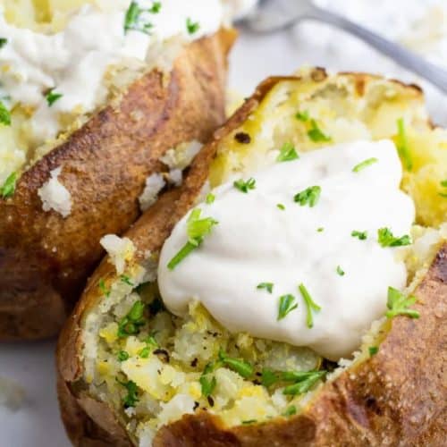 air fryer baked potatoes on white plate with vegan sour cream on top