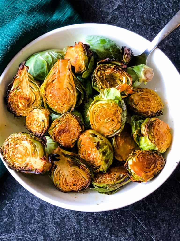 overhead of maple glazed Brussels sprouts in white bowl with spoon in it